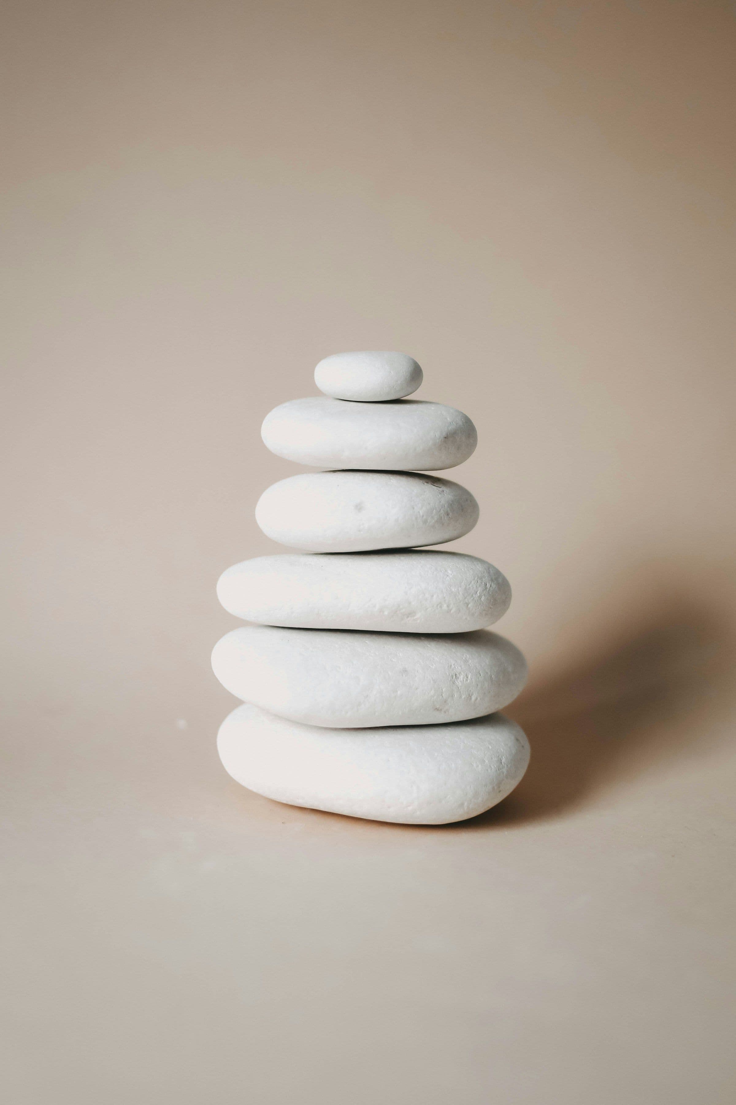 Piedras blancas apiladas en equilibrio sobre un fondo beige